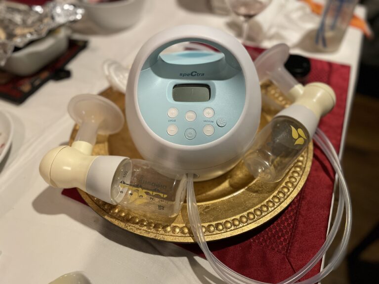 Spectra breast pump with Medela bottles on decorative charger